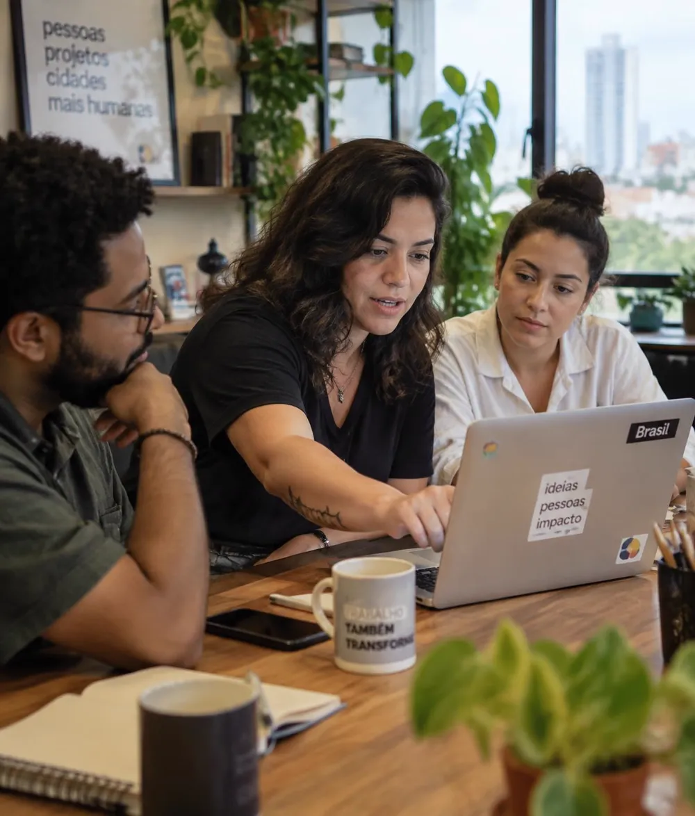 Time brasileiro reunido em volta de um notebook, discutindo uma decisão
